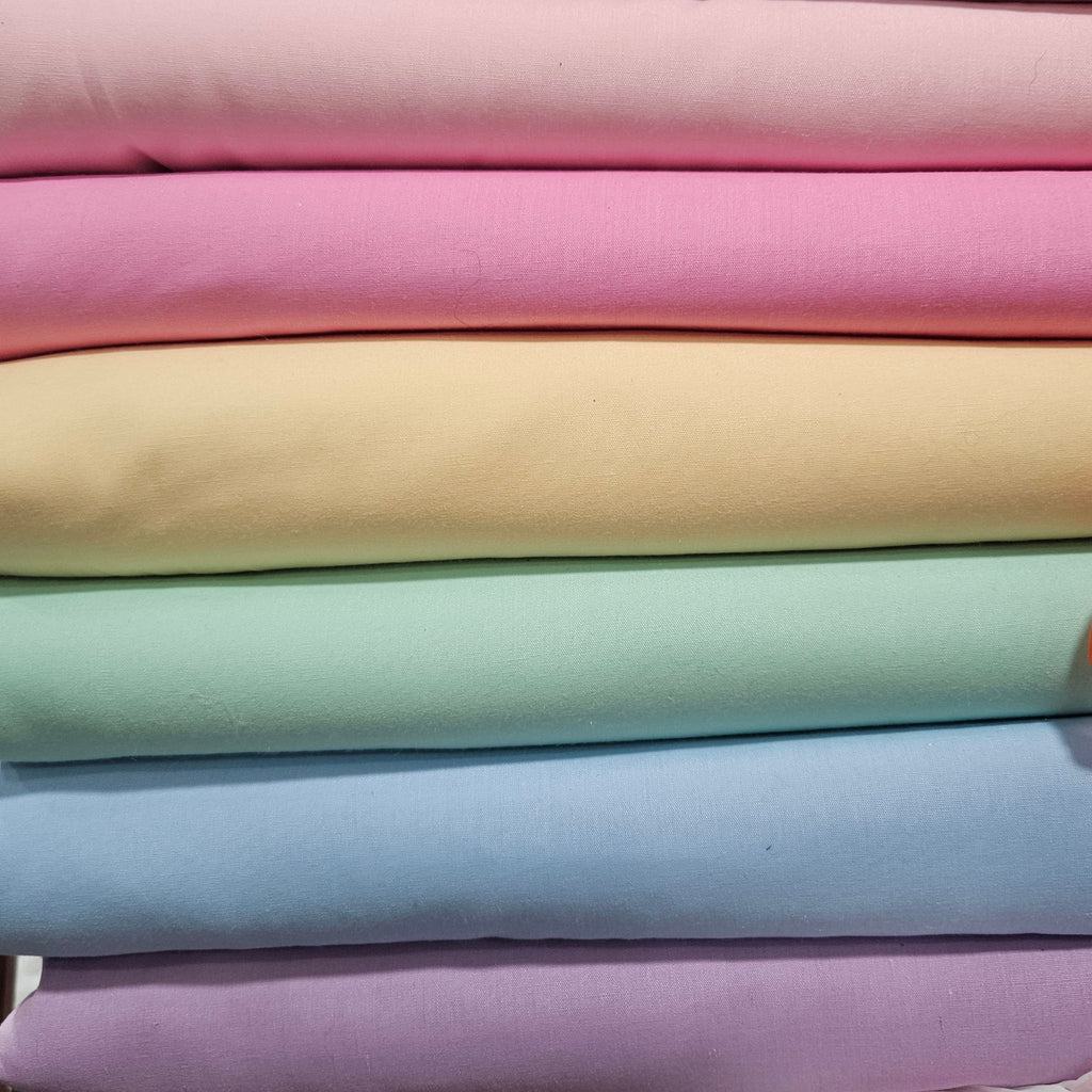 Stack of pastel-colored fabrics in various shades.