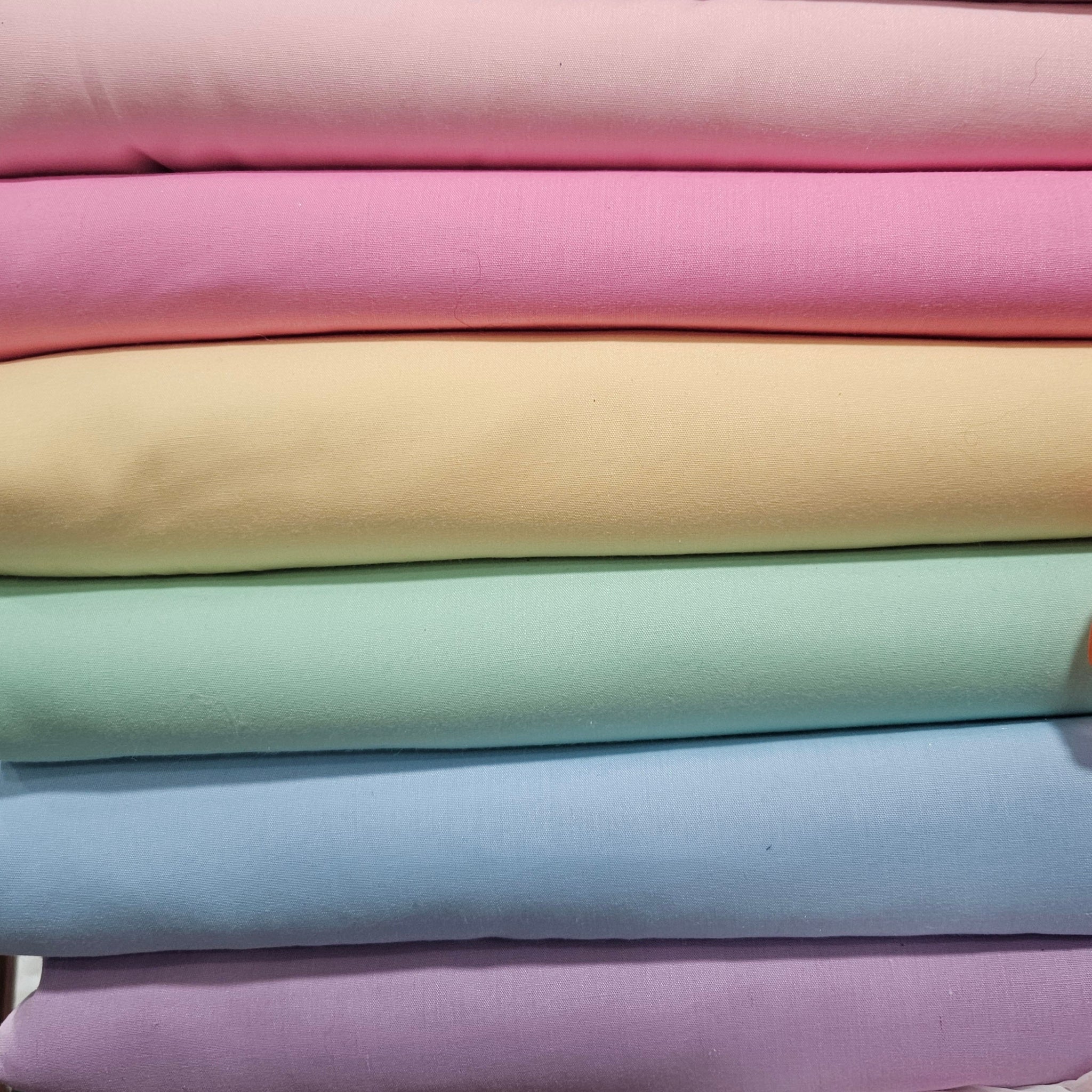 Stack of pastel-colored fabrics in various shades.