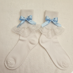 Pair of white socks with lace details and blue bows on a beige background