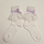 White socks with lace details and purple bows on a light gray background