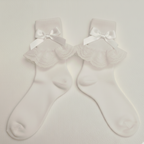 White socks with ruffled top and bow details on a light gray background