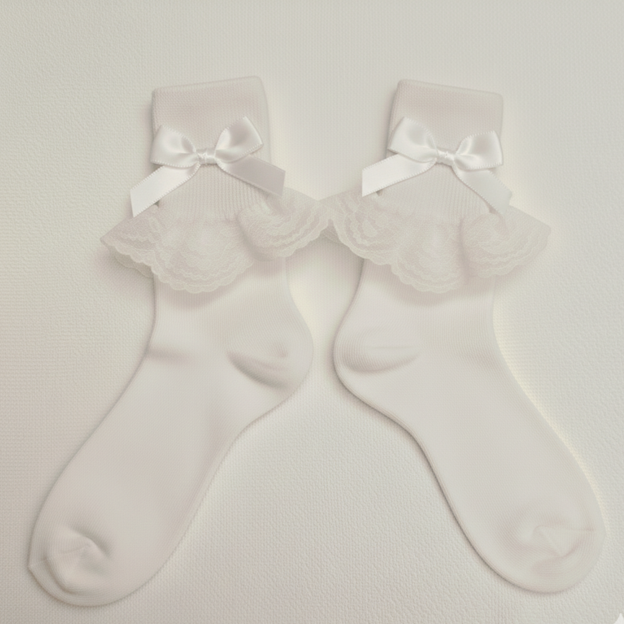 White socks with ruffled top and bow details on a light gray background