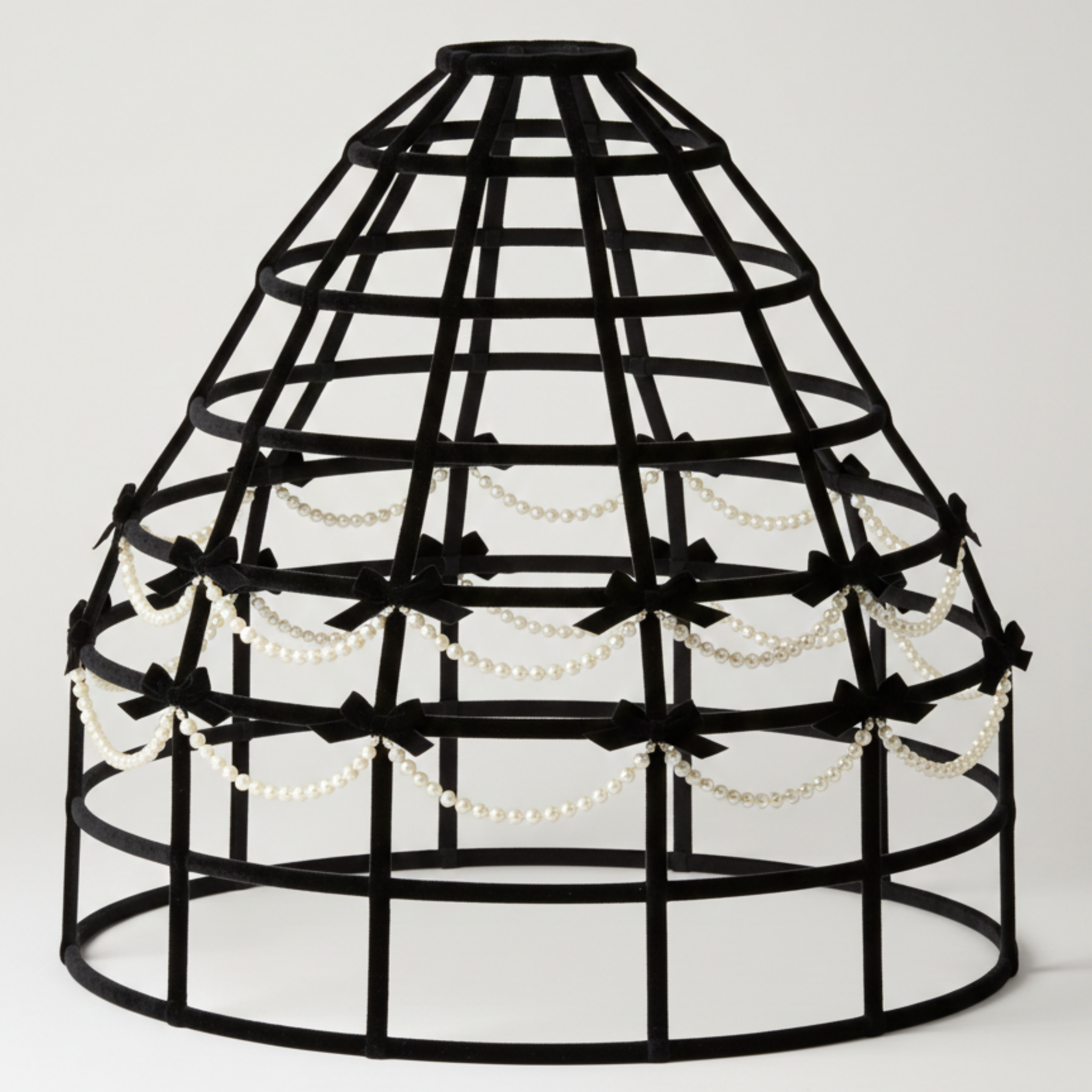 Black hoop skirt cage with decorative bows and beads on a white background