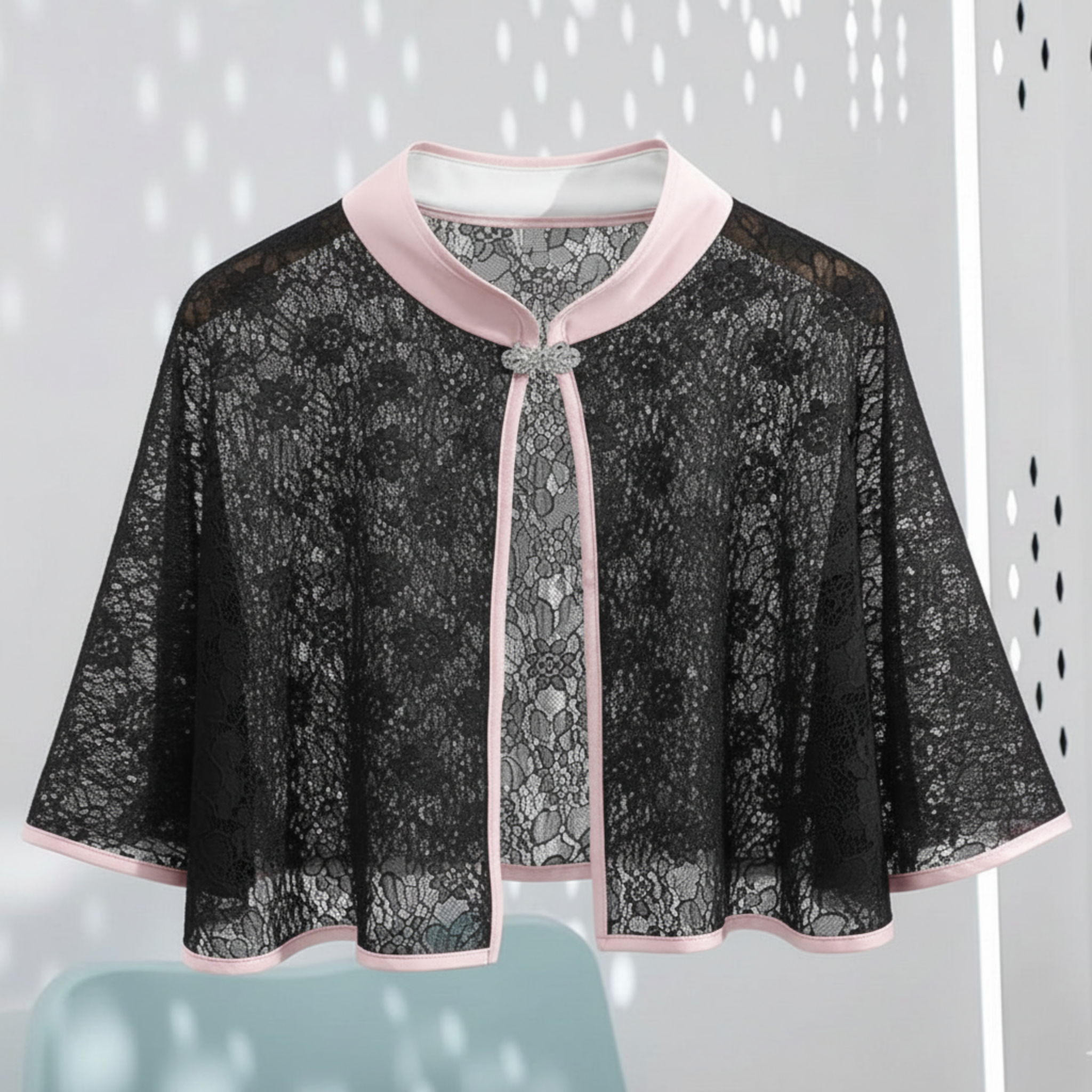 Black lace cape with pink trim on a light gray background