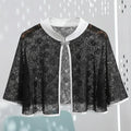 Black lace cape with white trim on a light gray background