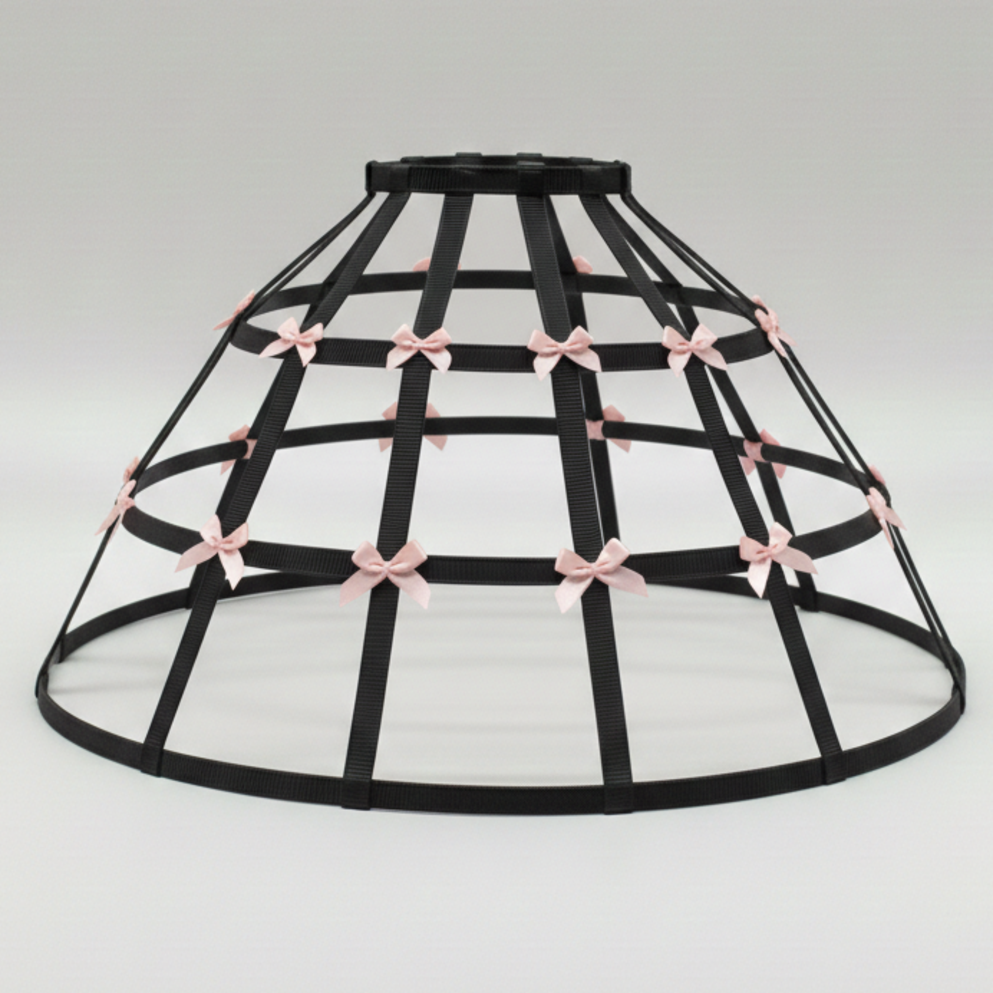 Black cage hoop skirt crinoline with pink accent bows on a white background