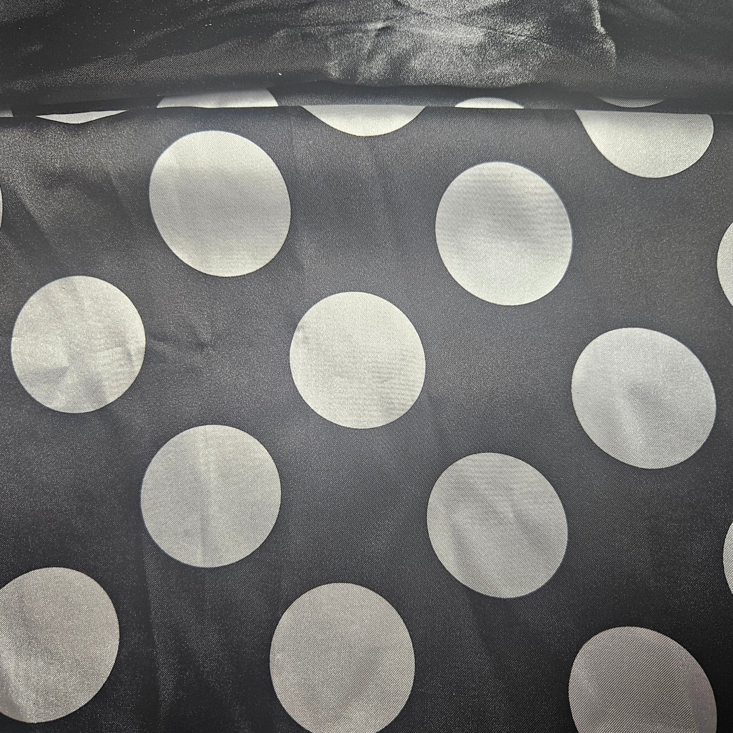 Black satin fabric with large white polka dots