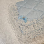 Close-up of a blue snuggle blanket with a floral embellishment and a light blue border.