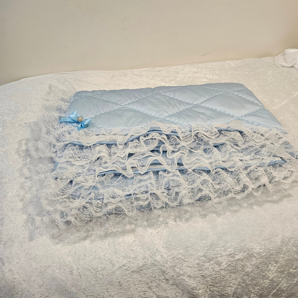 Close-up of a blue snuggle blanket with lace detailing on a neutral background