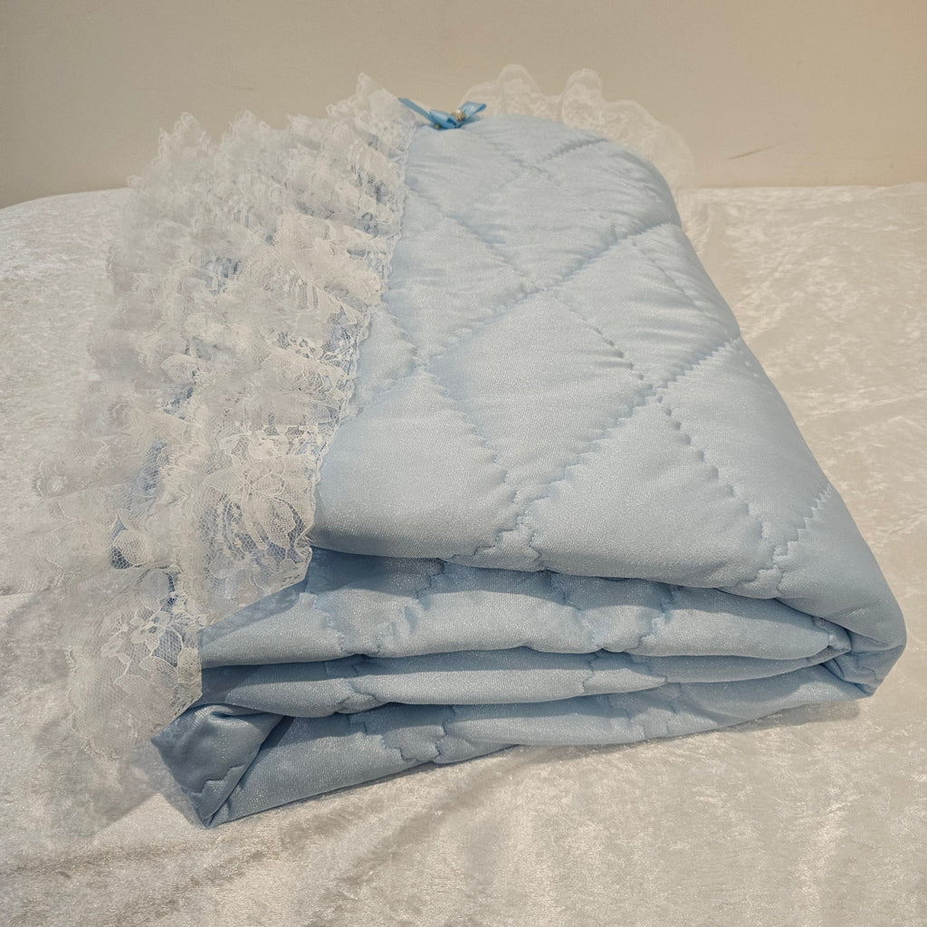 Folded light blue snuggle quilt on a textured surface