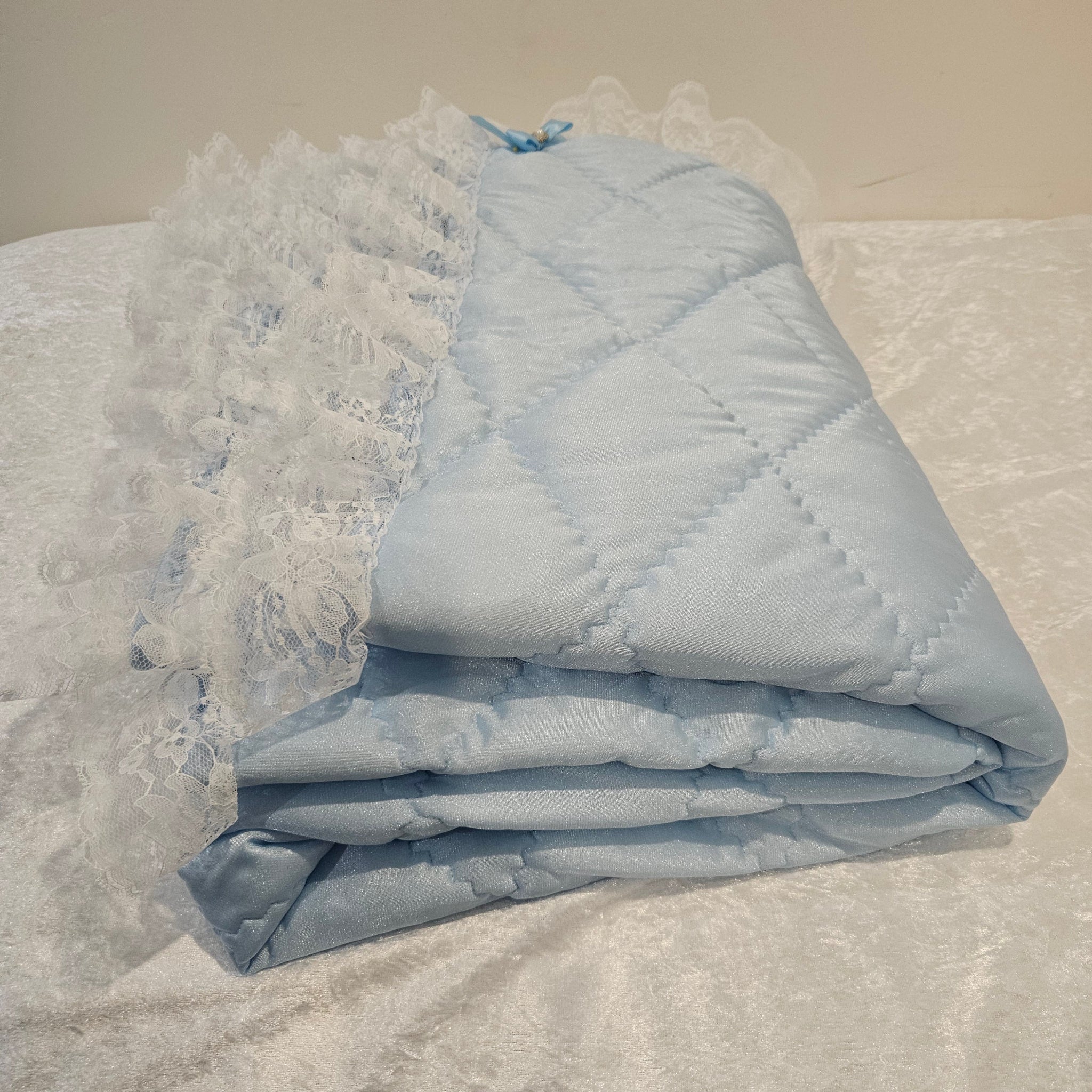 Folded light blue snuggle quilt on a textured surface