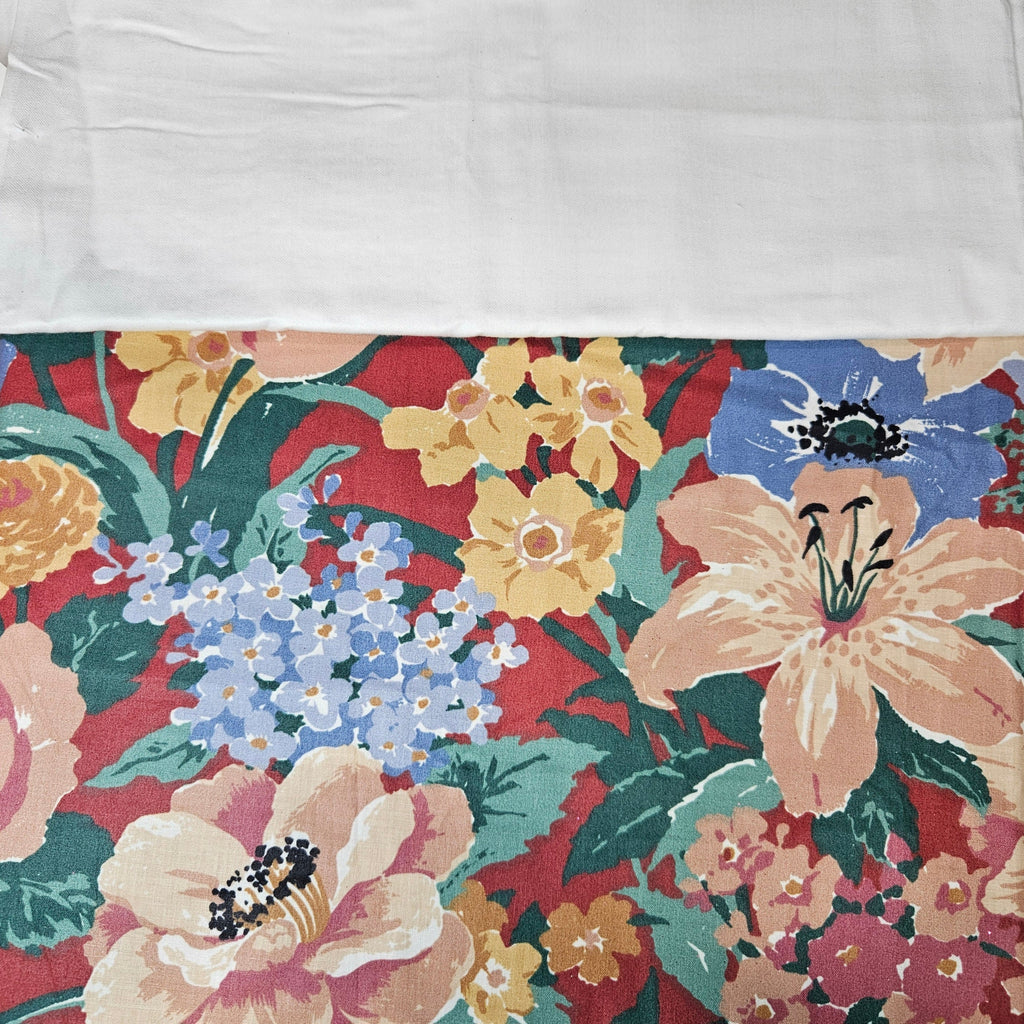 Floral fabric pattern with pink, yellow, and blue flowers on a red background.
