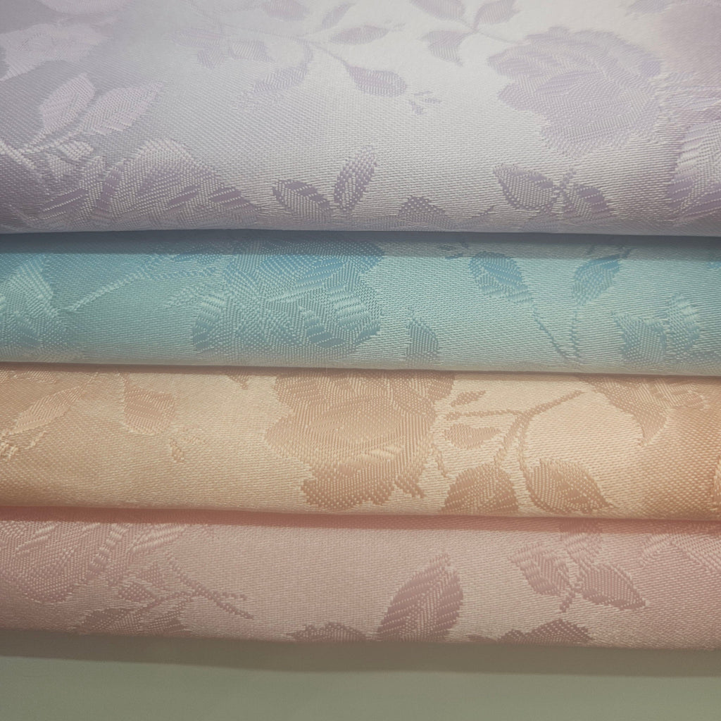 Stack of brocade fabric swatches with floral patterns in pastel colors.