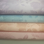 Stack of brocade fabric swatches with floral patterns in pastel colors.