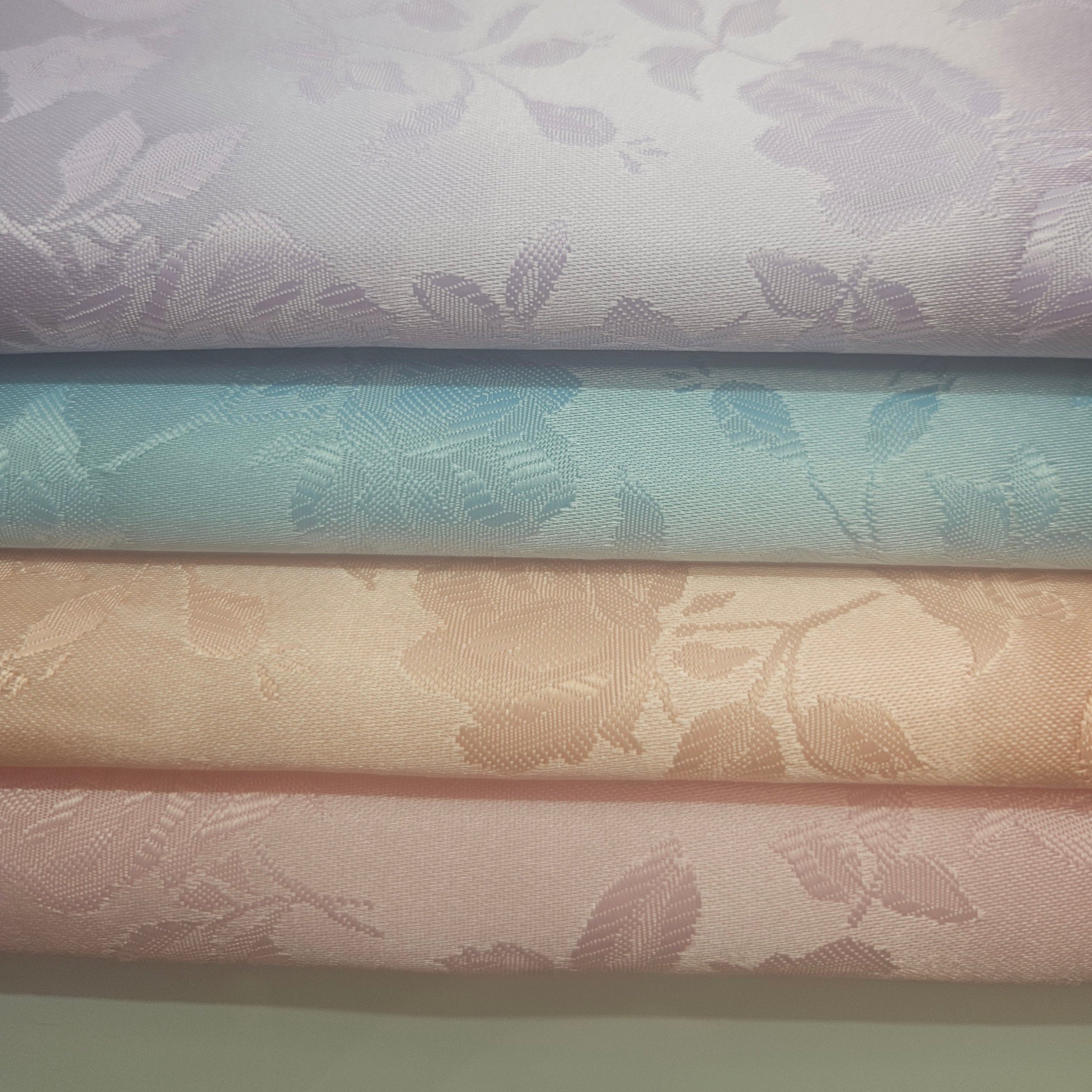 Stack of brocade fabric swatches with floral patterns in pastel colors.