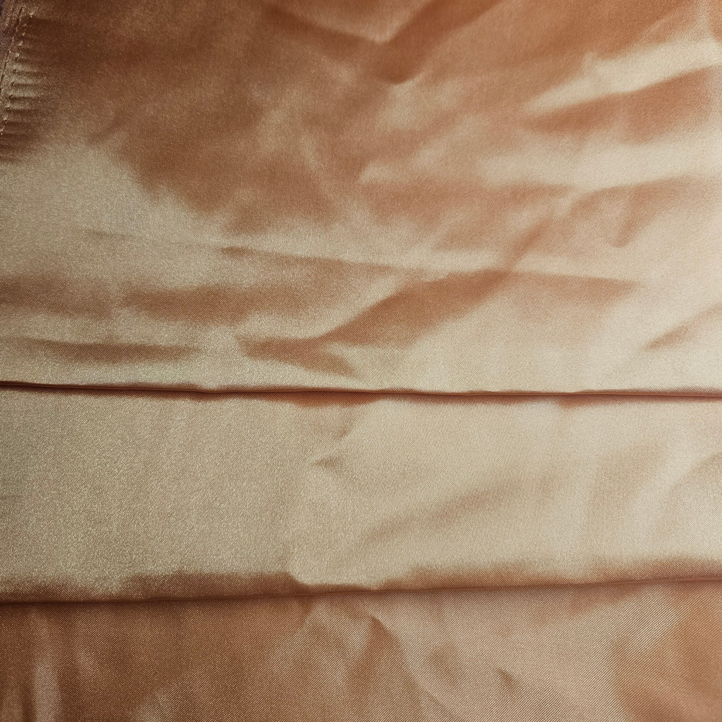 Close-up of dusty orange satin fabric with visible texture and folds