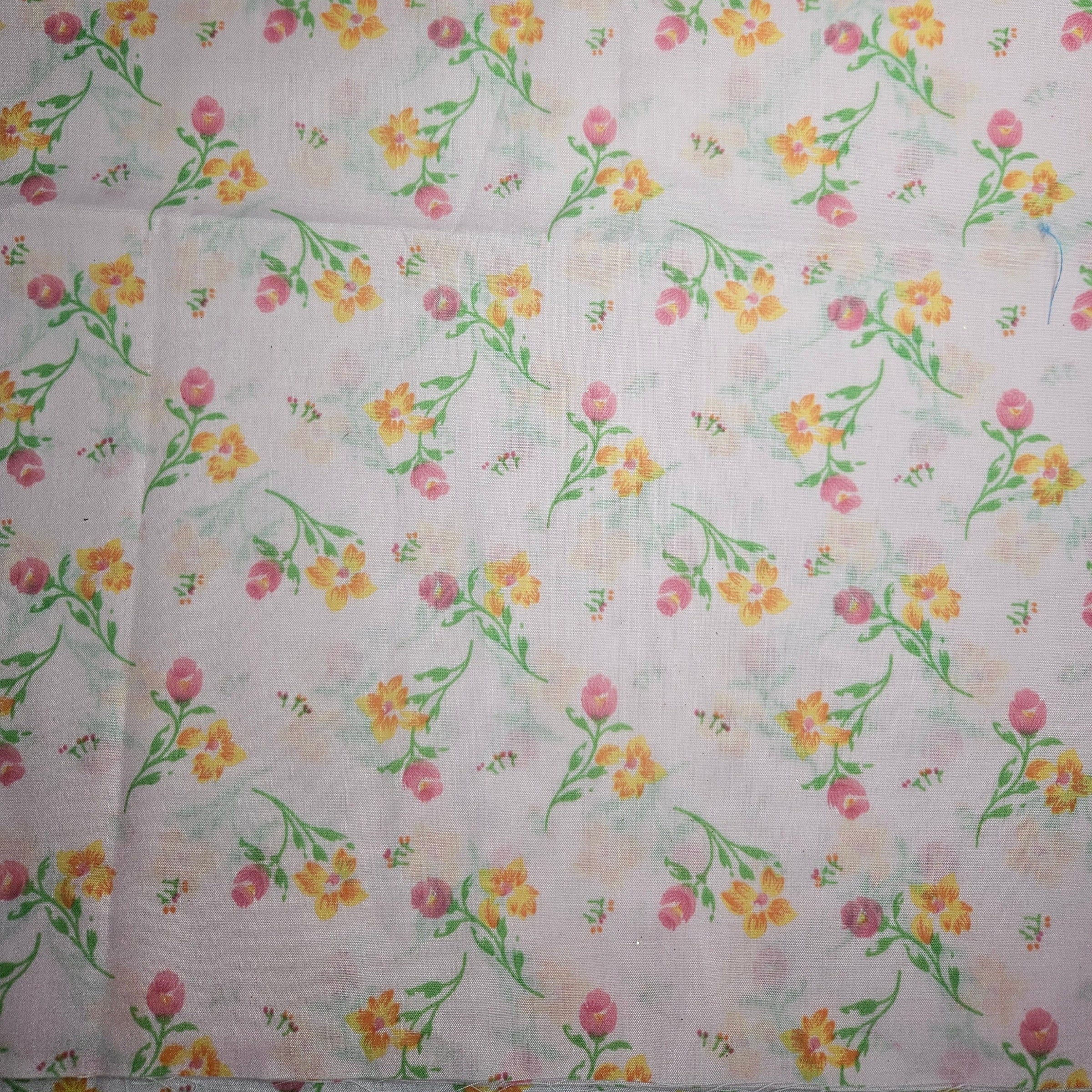 Floral patterned fabric with pink, yellow, and green flowers on a pink background