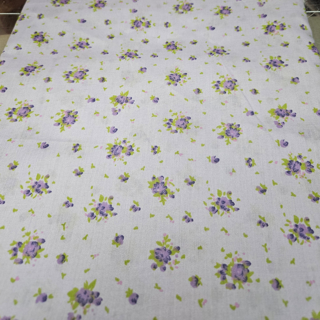Floral patterned fabric with purple flowers and green leaves on a lavender background