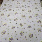 Floral patterned fabric with purple flowers and green leaves on a lavender background