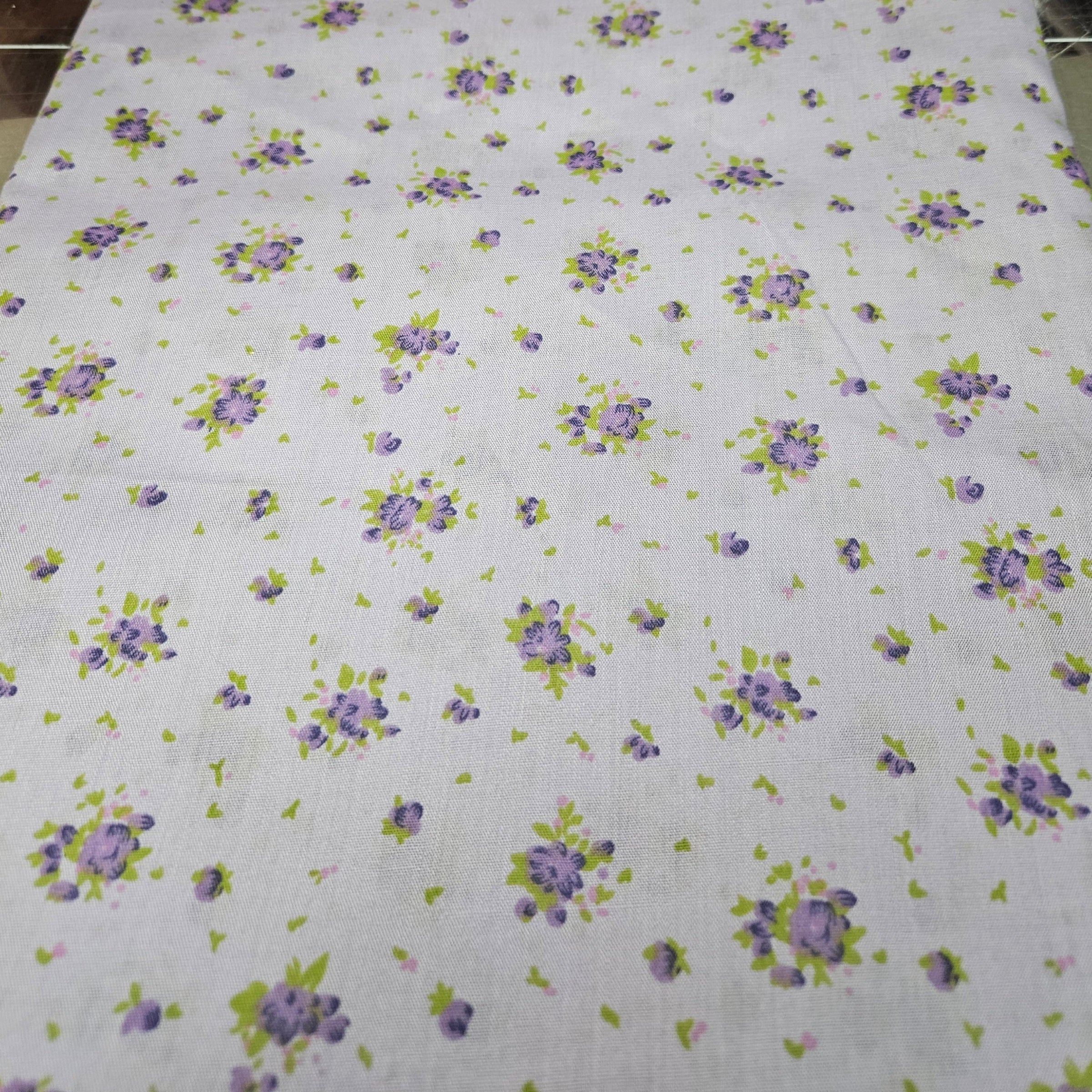 Floral patterned fabric with purple flowers and green leaves on a lavender background