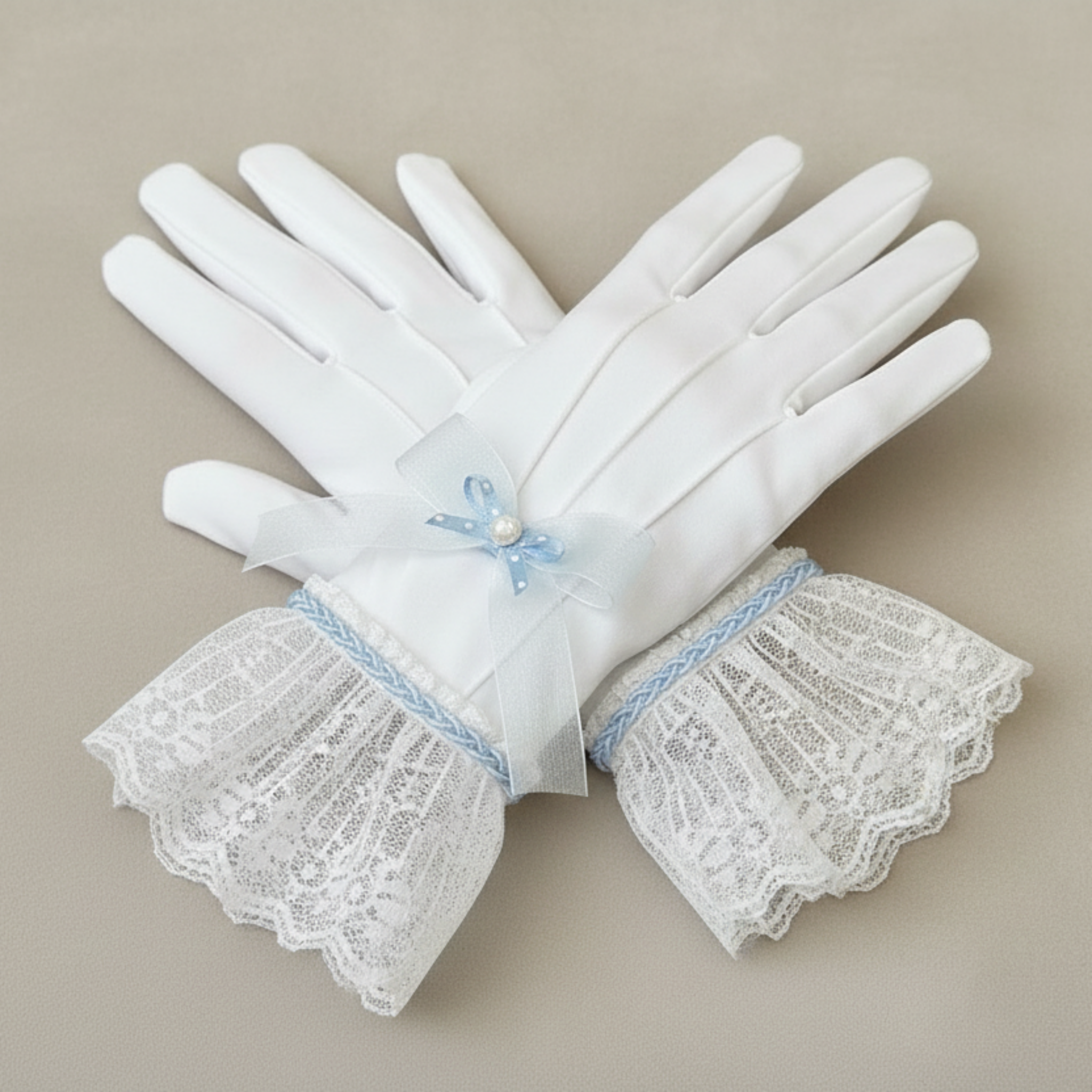 Pair of white gloves with lace cuffs on a beige background
