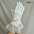White gloves with lace cuffs and a pink bow on a neutral background