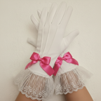 White lace gloves with pink ribbon bows on a neutral background