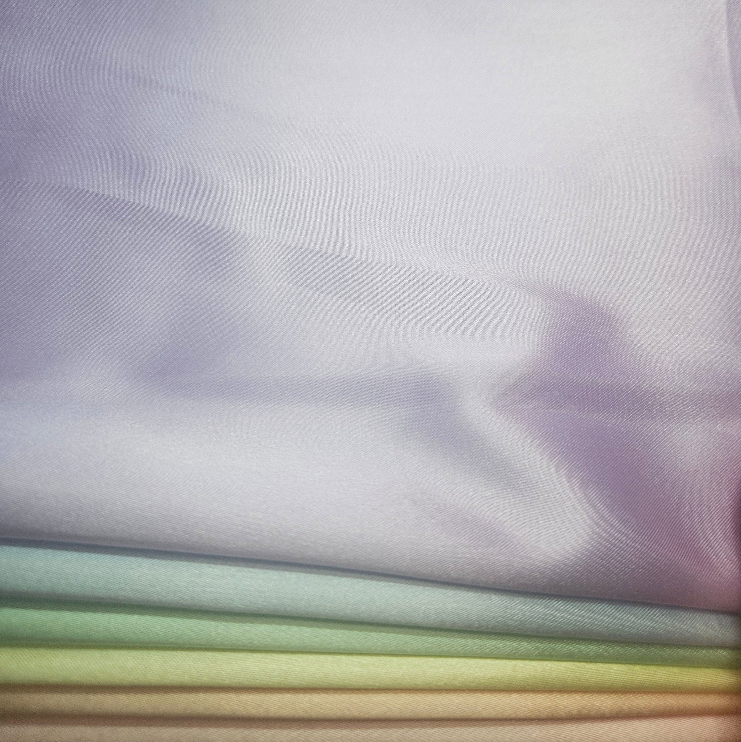 Stack of pastel-colored fabrics including yellow, peach, pink, purple, blue, & mint green