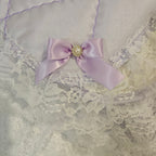 satin bow with a decorative center on a lavender snuggle blanket with  white fabric background