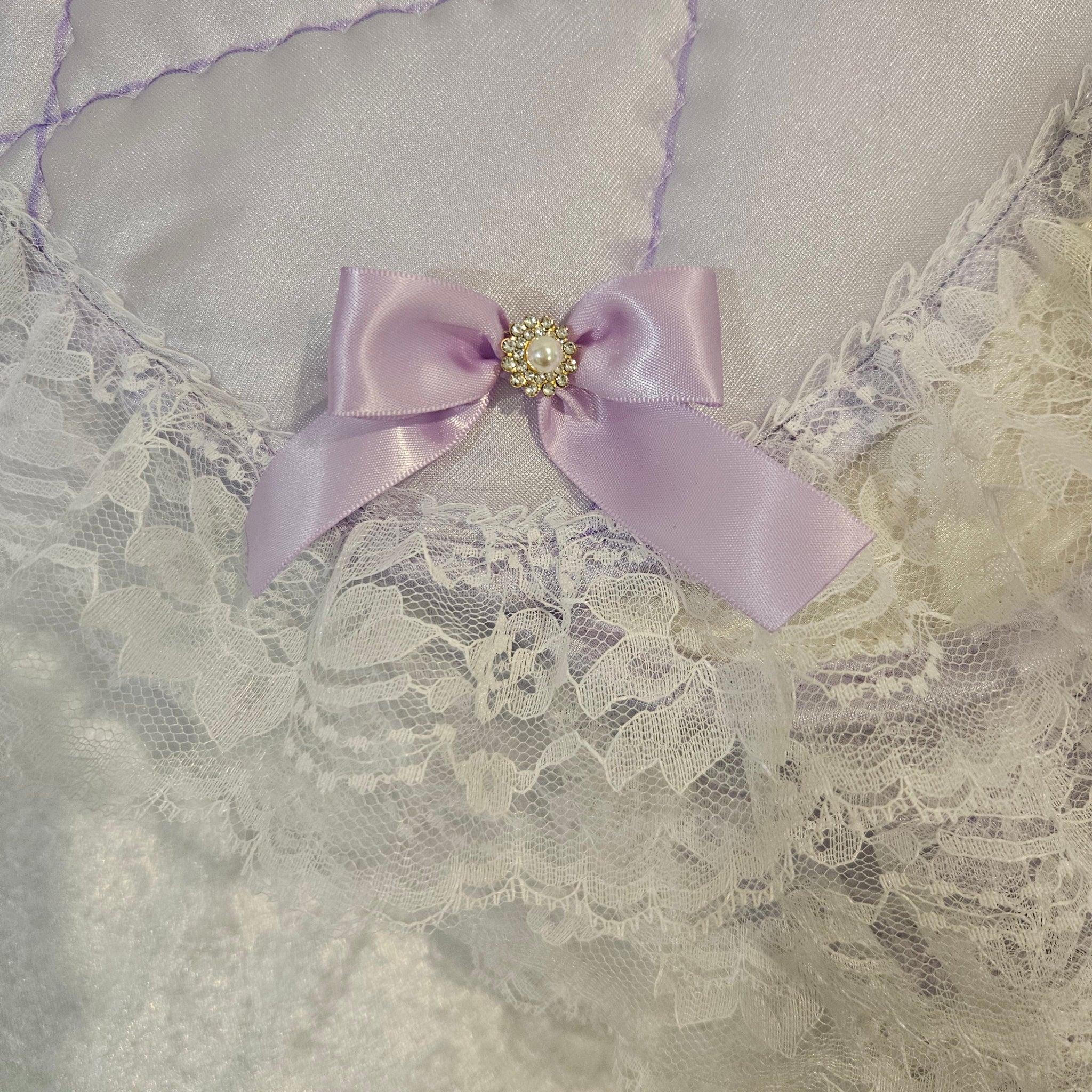 satin bow with a decorative center on a lavender snuggle blanket with  white fabric background