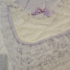 Close-up of a lavender snuggle blanket with lace detailing and a purple bow.