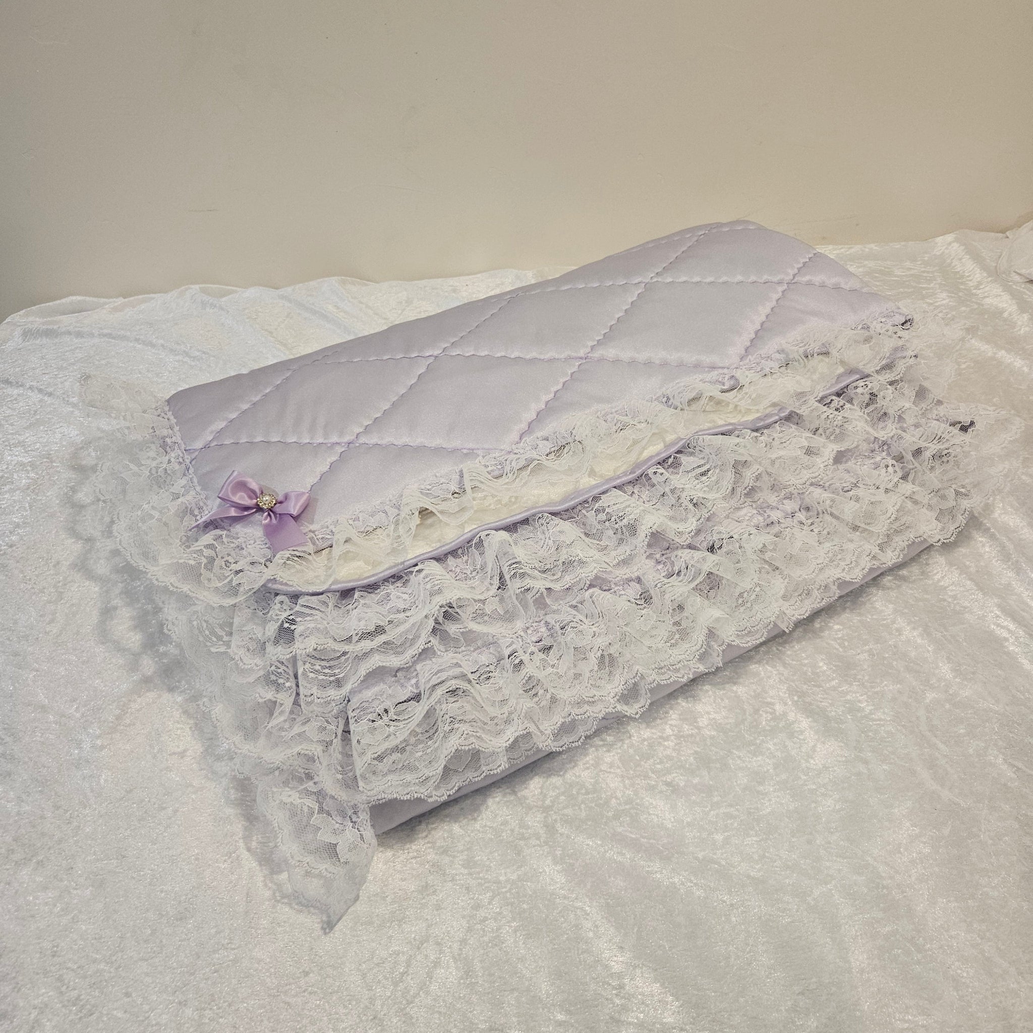 Lavender snuggle quilt with lace trim on a light gray background