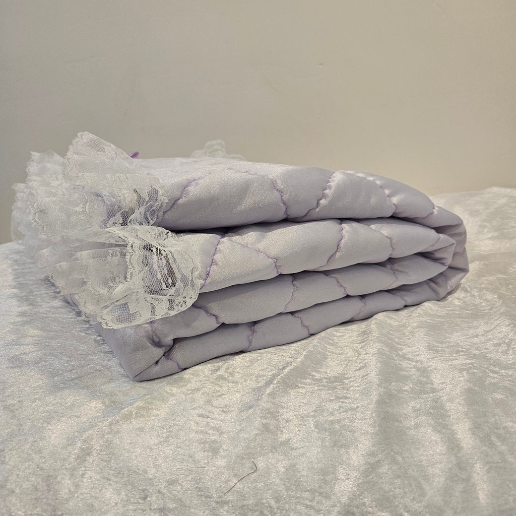 Lavender Snuggle quilt with lace trim draped over a textured surface