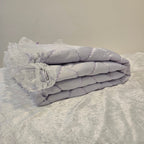 Lavender Snuggle quilt with lace trim draped over a textured surface