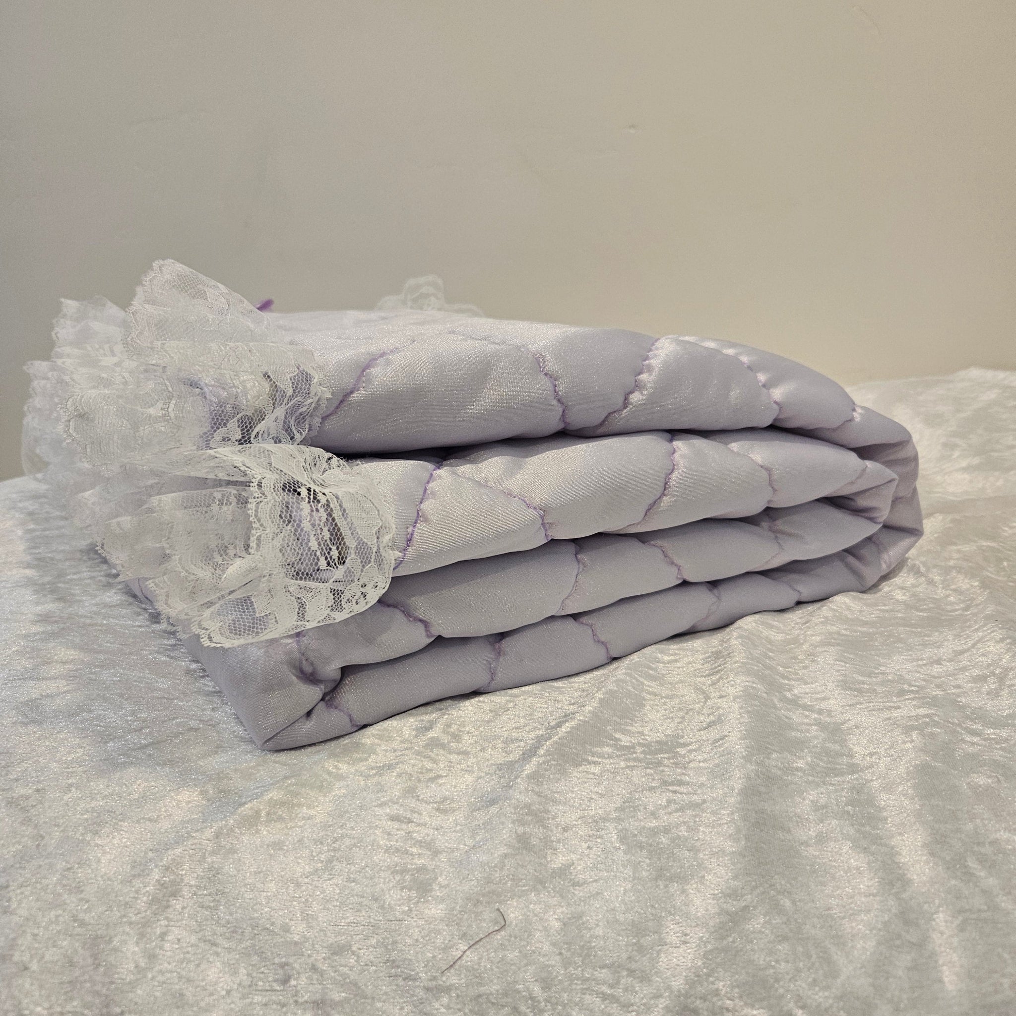 Lavender Snuggle quilt with lace trim draped over a textured surface