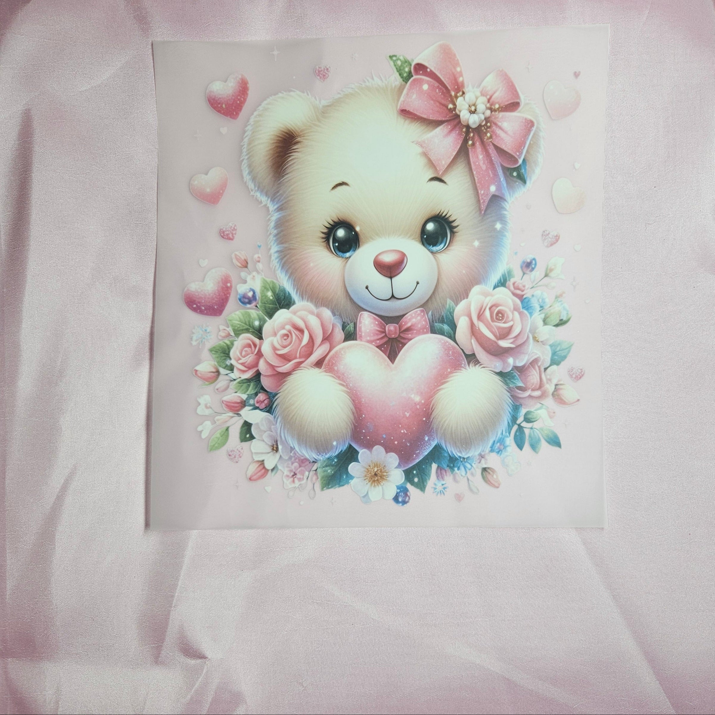 Cartoon bear applique with a bow and flowers on a pink taffeta background