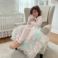 Child sitting on a chair with a pink and mint green snuggle blanket in a nursery setting