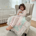 Child sitting on a chair with a pink and mint green snuggle blanket in a nursery setting