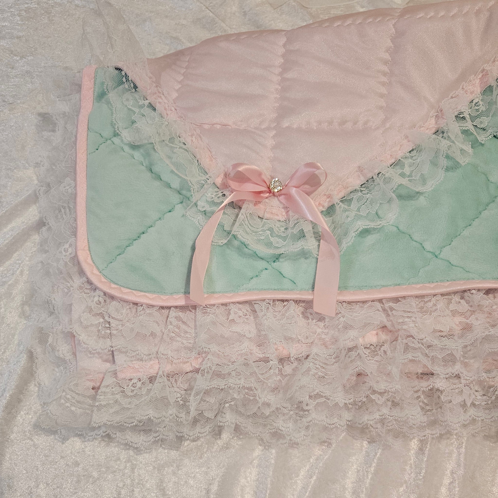 Adult Baby snuggle quilt with pink and green design on a textured surface