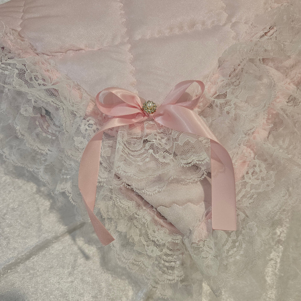 Lace garment with a pink ribbon on a snuggle blanket with a textured surface