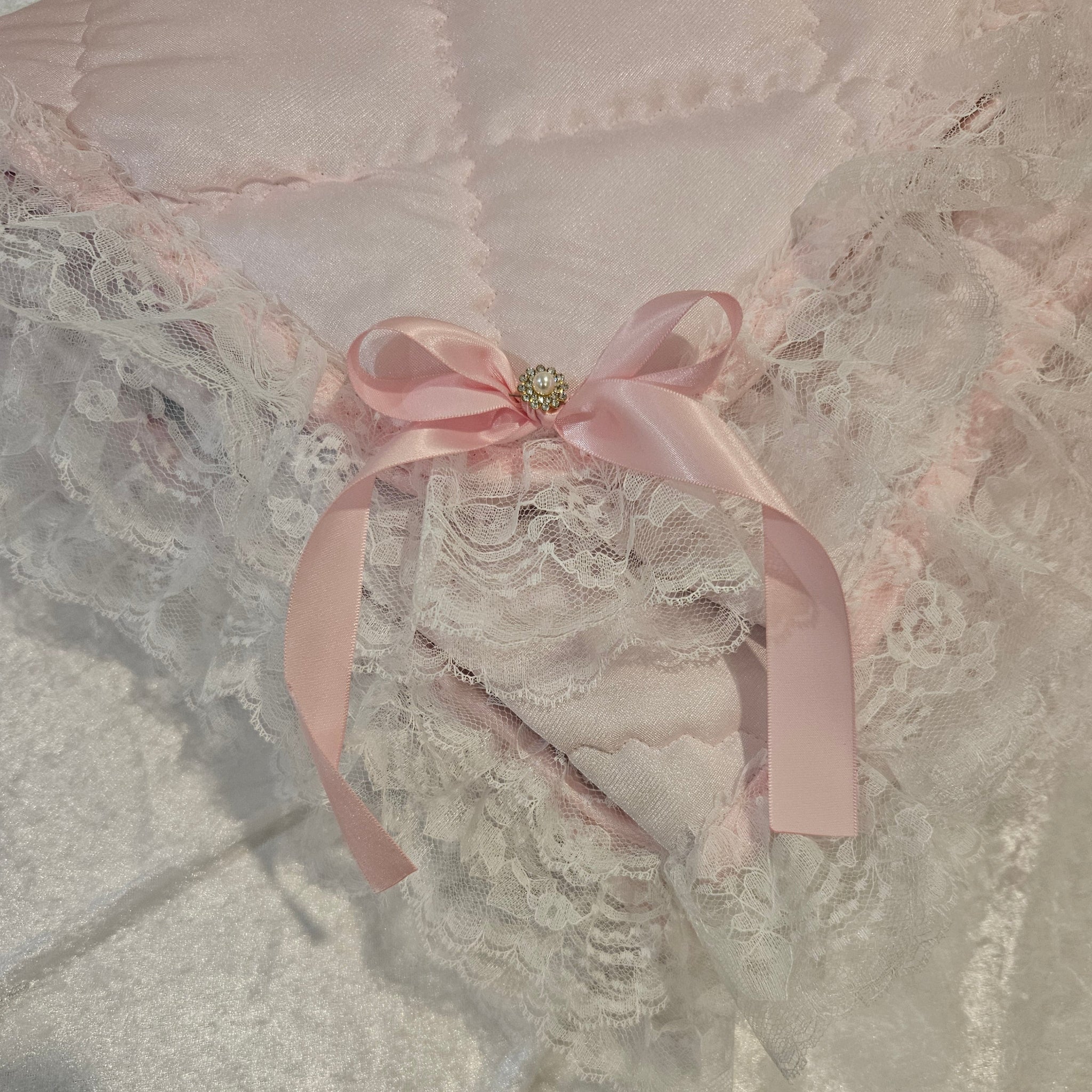 Lace garment with a pink ribbon on a snuggle blanket with a textured surface