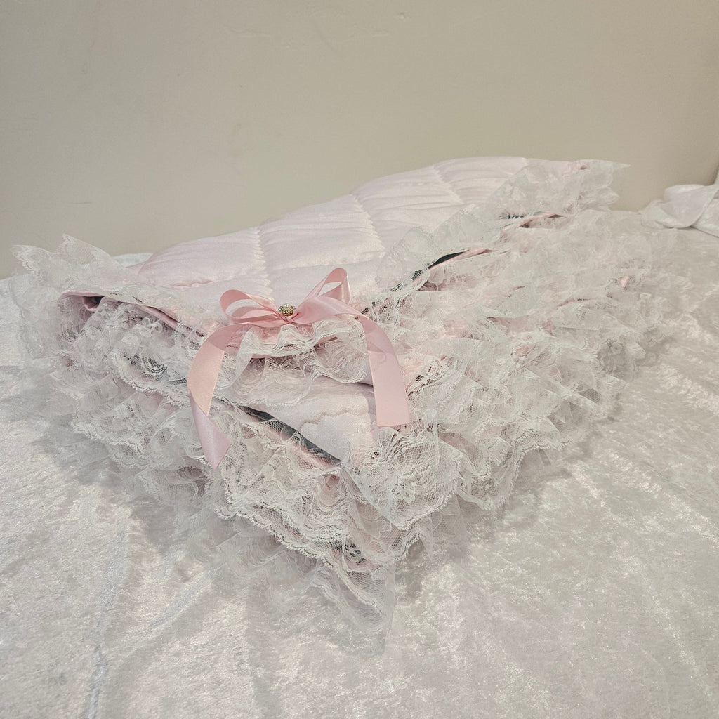 Close-up of a lace snuggle blanket with a pink ribbon on a plain background