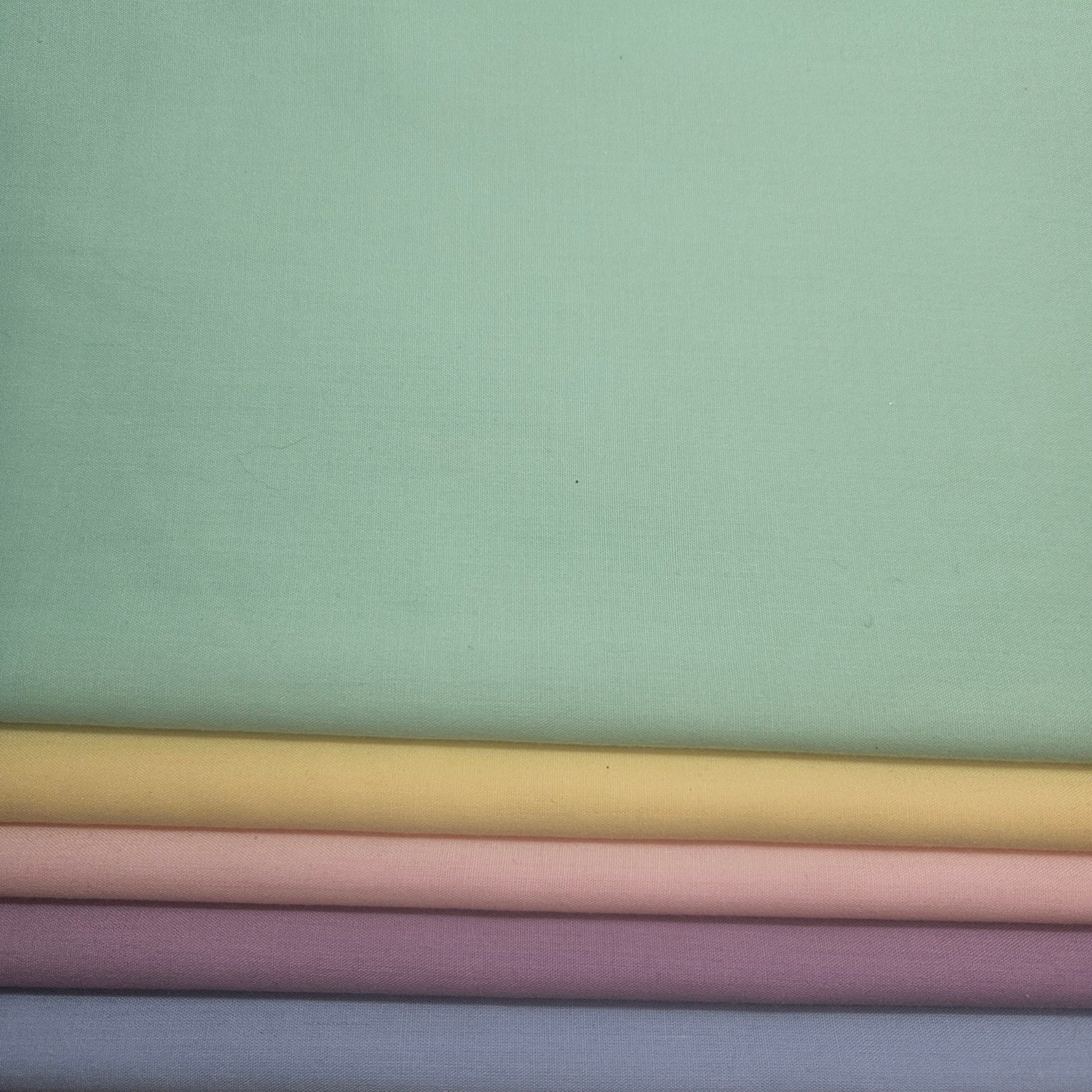 Stack of pastel-colored fabric swatches on a light green broadcloth background