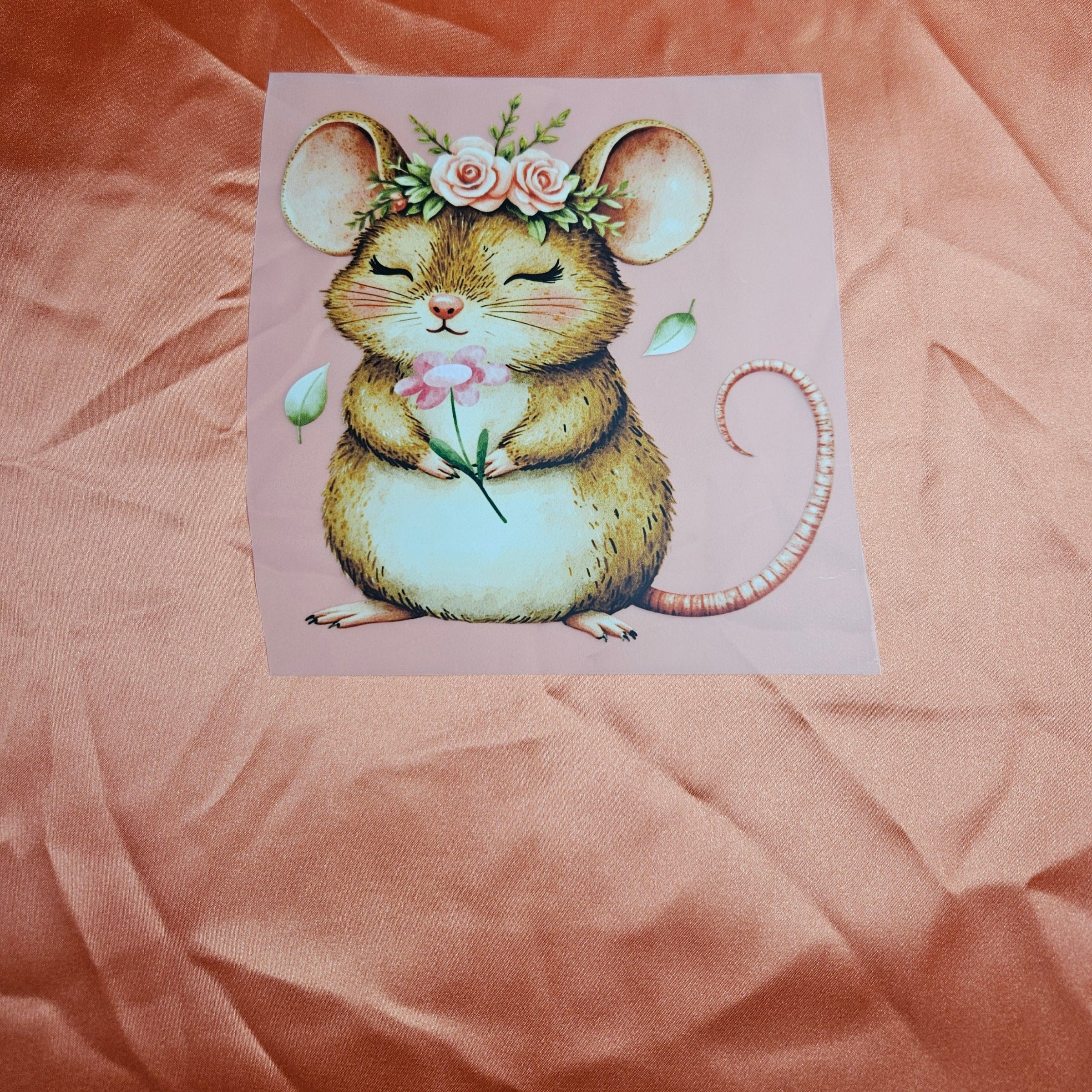 Illustration of a mouse with a flower applique on an orange satin fabric background