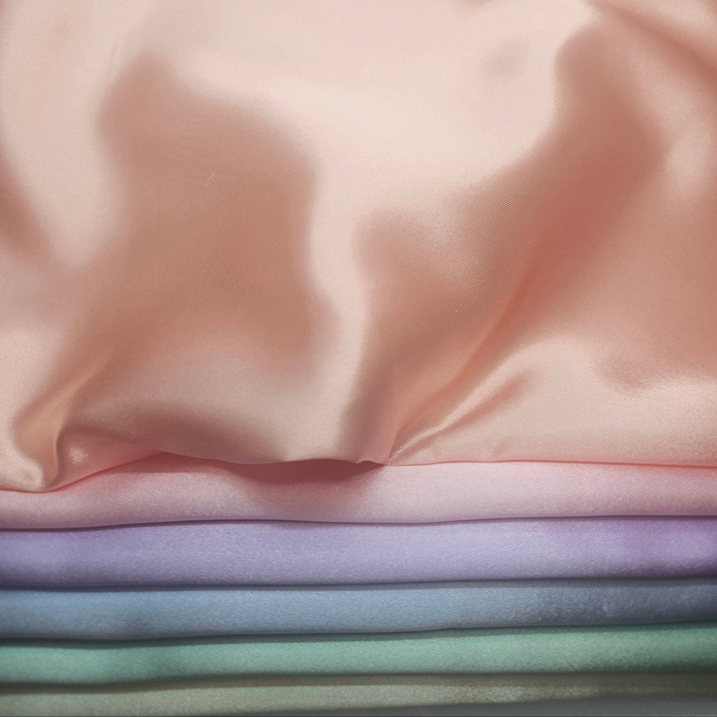 Stack of pastel-colored satin fabrics Peach