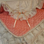 Peach snuggle blanket with lace trim and a bow and minky dots on a textured surface