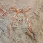 Lace peach snuggle blanket with a peach ribbon bow and decorative element on a textured background