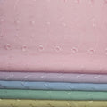 Stack of fabric swatches with floral patterns on a pink eyelet background