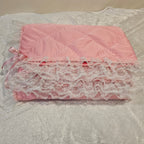 Pink Minky snuggle blanket with lace trim on a textured surface