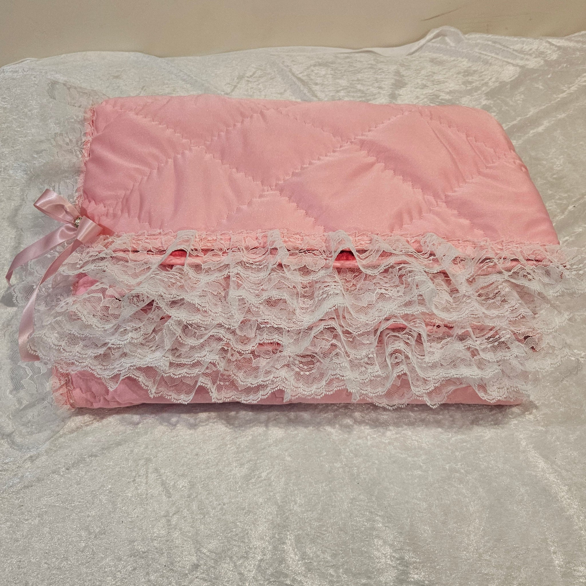 Pink Minky snuggle blanket with lace trim on a textured surface